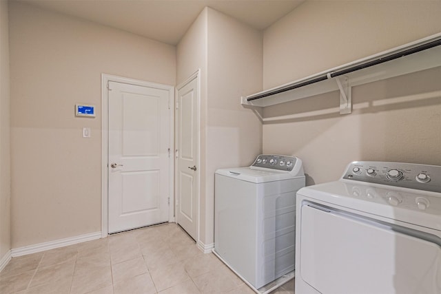 laundry area with laundry area, light tile patterned flooring, baseboards, and washer and clothes dryer