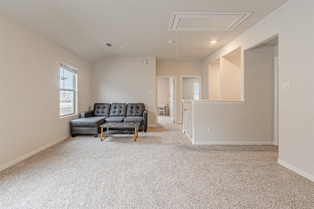 carpeted living room with visible vents, baseboards, attic access, and vaulted ceiling