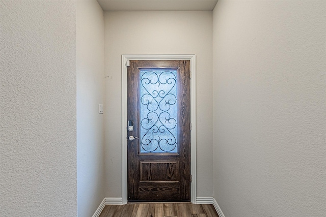 entryway with baseboards, a textured wall, and dark wood-style flooring