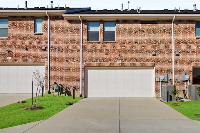 view of front of house featuring brick siding, an attached garage, concrete driveway, and central AC