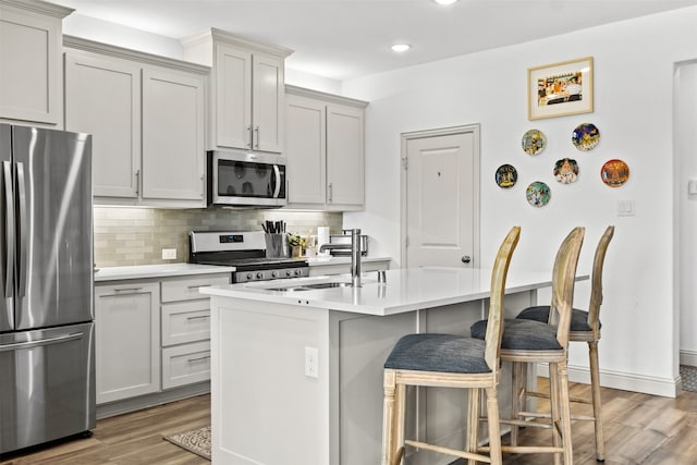 kitchen with tasteful backsplash, a breakfast bar area, light countertops, light wood-style floors, and stainless steel appliances