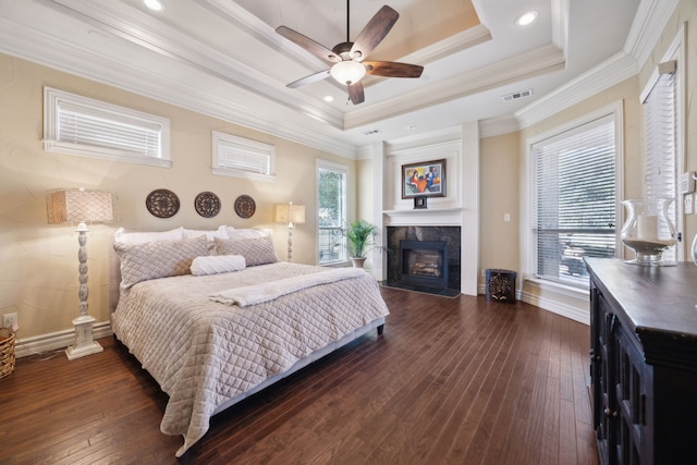 bedroom featuring dark wood finished floors, visible vents, crown molding, and a raised ceiling