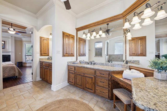 bathroom featuring stone tile floors, ensuite bathroom, crown molding, and a ceiling fan