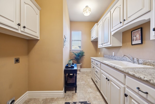 washroom featuring cabinet space, baseboards, hookup for an electric dryer, and a sink