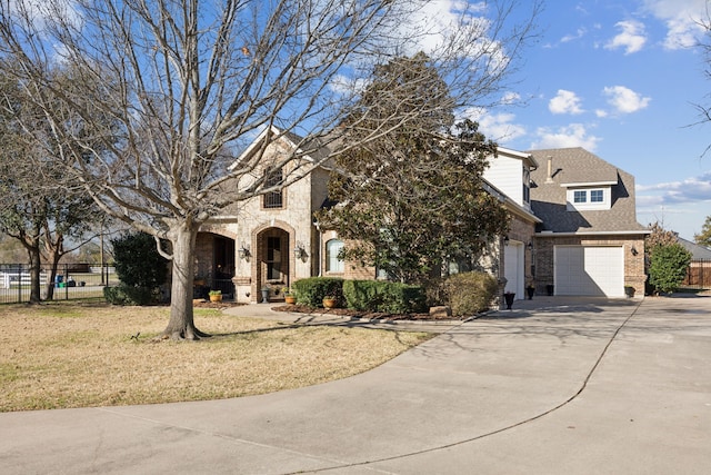 view of front of property featuring stone siding, fence, roof with shingles, concrete driveway, and brick siding