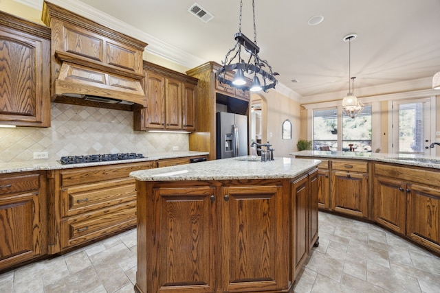 kitchen with visible vents, stainless steel refrigerator with ice dispenser, black gas cooktop, a sink, and a center island