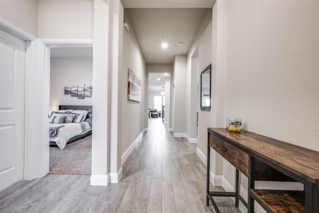 corridor featuring light wood finished floors and baseboards