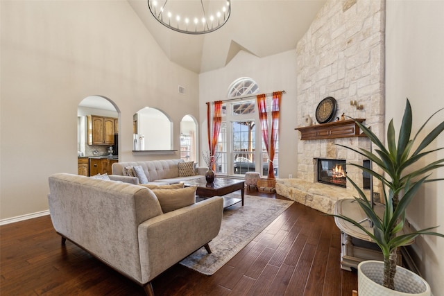 living area featuring arched walkways, a fireplace, baseboards, and dark wood-style flooring