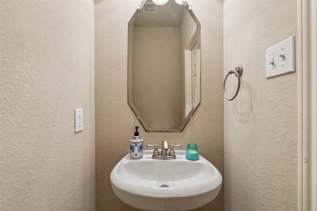 bathroom with a textured wall, visible vents, and a sink