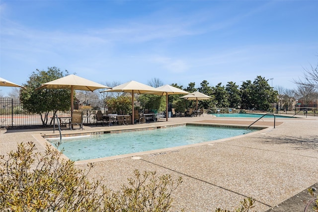 community pool with a patio area and fence