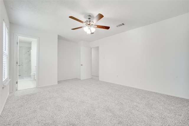 unfurnished bedroom featuring visible vents, ceiling fan, light colored carpet, ensuite bathroom, and a textured ceiling