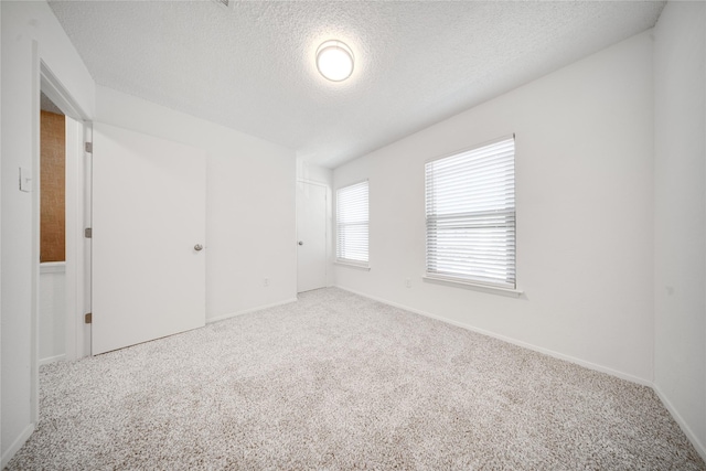 unfurnished room featuring carpet flooring, baseboards, and a textured ceiling