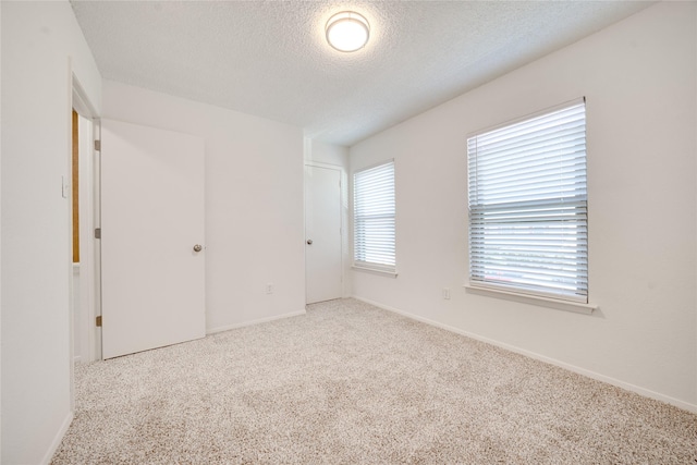 unfurnished bedroom featuring baseboards, a textured ceiling, and carpet