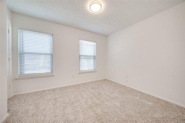 unfurnished room featuring carpet flooring, a textured ceiling, and baseboards