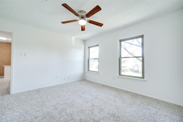 empty room with baseboards, a textured ceiling, a ceiling fan, and carpet