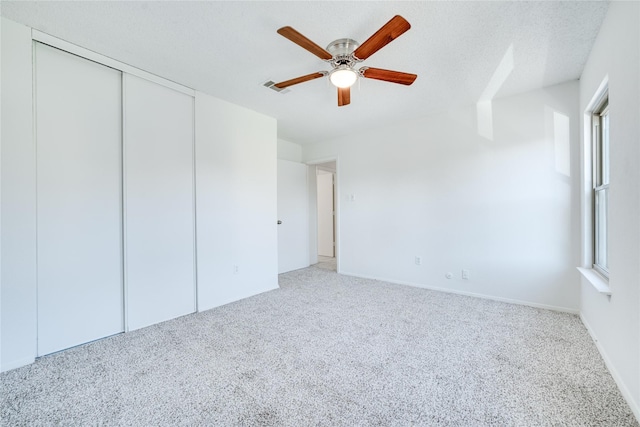 unfurnished bedroom with a ceiling fan, visible vents, carpet floors, a closet, and a textured ceiling