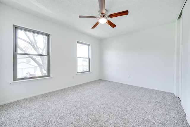 carpeted empty room with ceiling fan, baseboards, and a textured ceiling