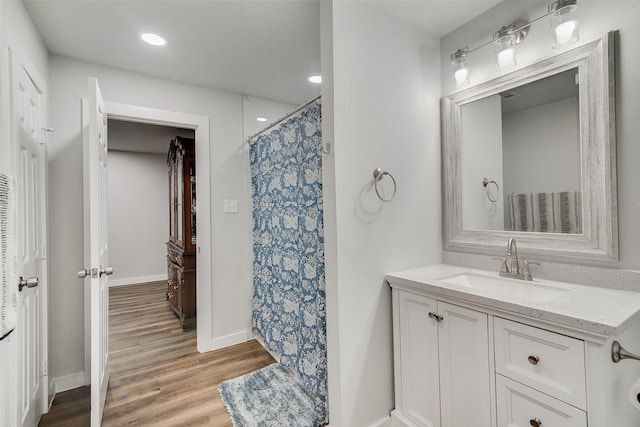 full bathroom featuring curtained shower, baseboards, recessed lighting, wood finished floors, and vanity