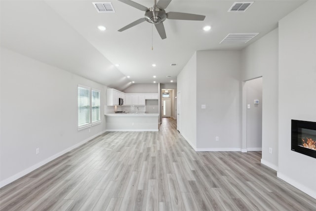 unfurnished living room featuring visible vents, light wood-type flooring, and a glass covered fireplace