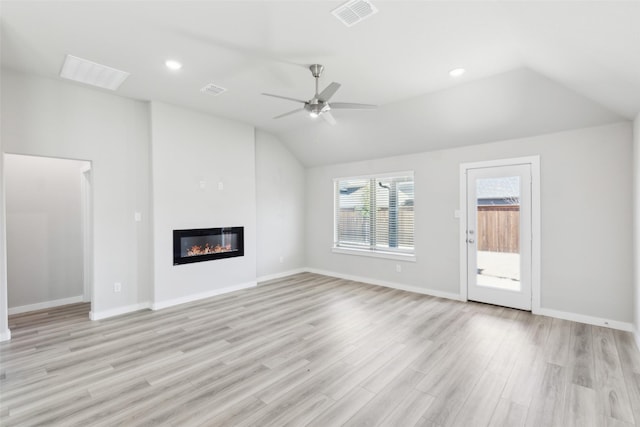 unfurnished living room with a glass covered fireplace, visible vents, light wood-type flooring, and lofted ceiling