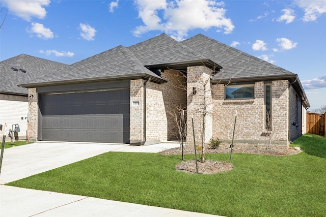 view of front of house with a garage, driveway, roof with shingles, and a front yard