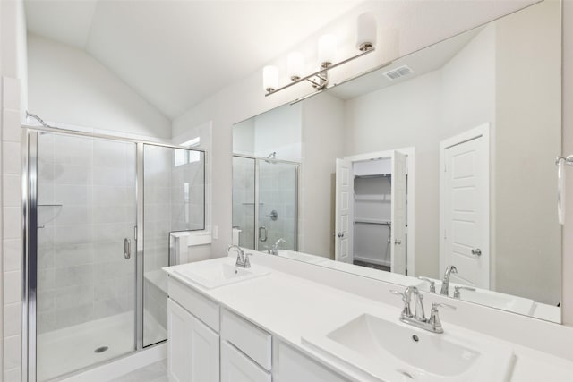 bathroom featuring a sink, visible vents, a shower stall, and vaulted ceiling