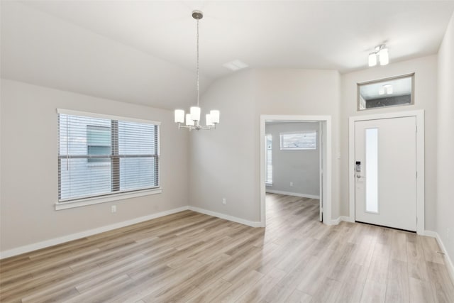 entryway featuring vaulted ceiling, light wood-style flooring, a wealth of natural light, and a chandelier