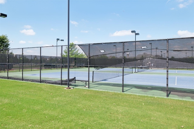 view of sport court with a yard and fence