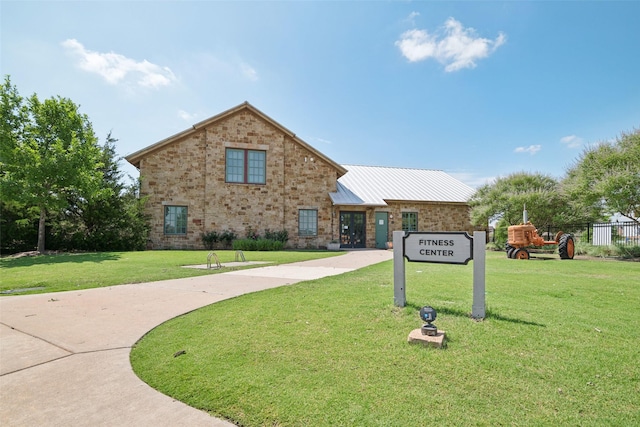 view of front of home featuring metal roof, brick siding, and a front lawn