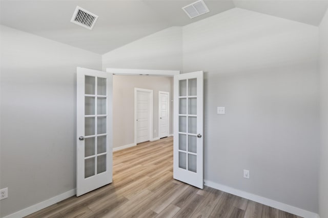 unfurnished room with visible vents, french doors, lofted ceiling, and wood finished floors