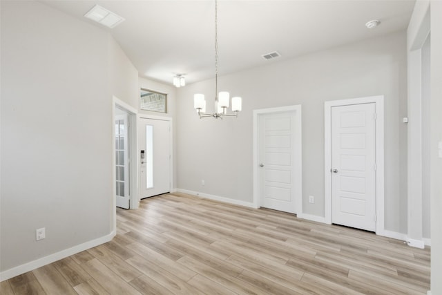 unfurnished dining area with baseboards, light wood-style floors, visible vents, and a chandelier