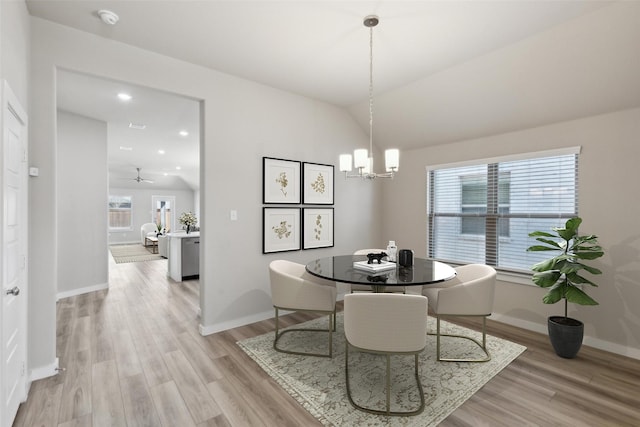 dining area featuring a notable chandelier, baseboards, light wood-style floors, and vaulted ceiling