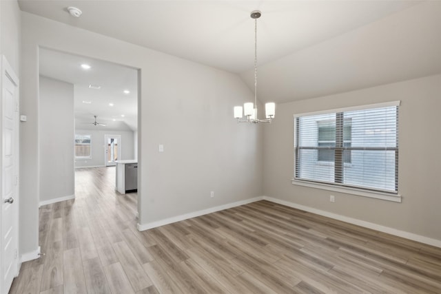 spare room featuring baseboards, an inviting chandelier, light wood-style flooring, and vaulted ceiling