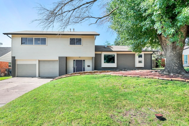 tri-level home featuring a garage, driveway, brick siding, and a front yard