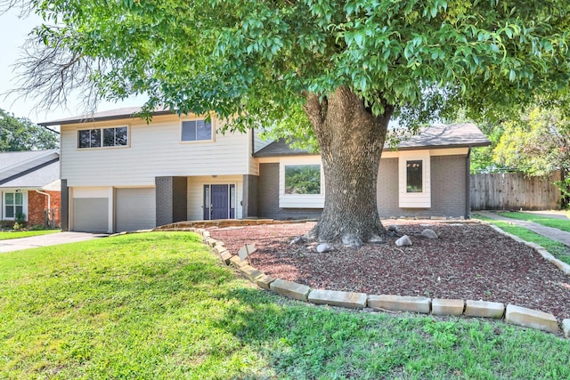 view of front of home featuring a front lawn, fence, brick siding, and driveway