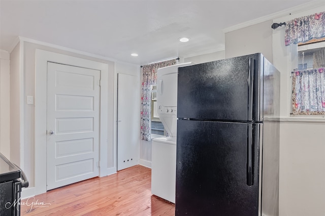 kitchen featuring freestanding refrigerator, recessed lighting, light wood-style floors, crown molding, and stacked washer / drying machine