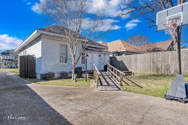 view of front of home with entry steps, central AC unit, a front lawn, and fence