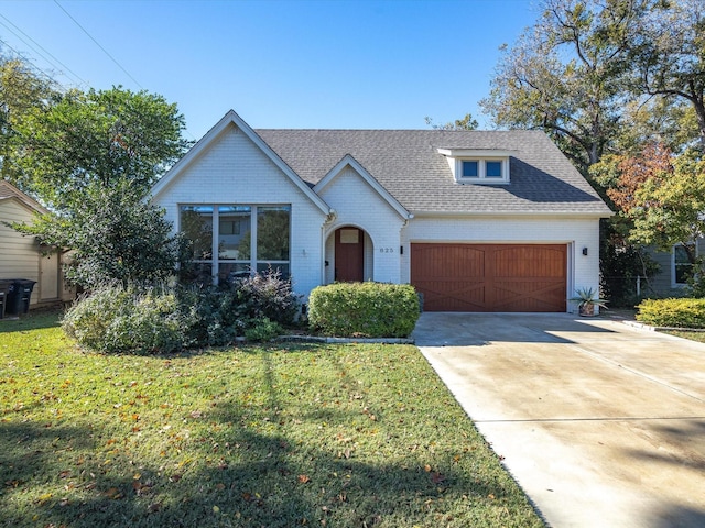 view of front of property featuring brick siding, a front lawn, a shingled roof, and a garage