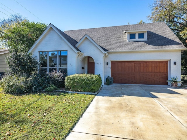 view of front of property with brick siding, concrete driveway, a front yard, roof with shingles, and a garage