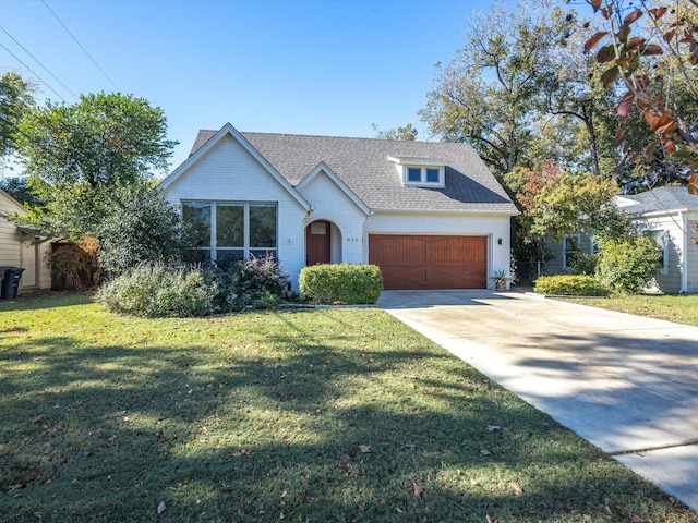 view of front of property featuring driveway, roof with shingles, a front lawn, a garage, and brick siding