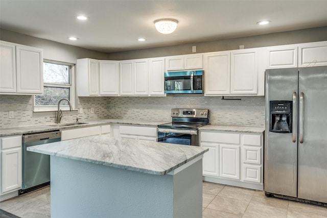 kitchen featuring a sink, a kitchen island, stainless steel appliances, white cabinets, and light stone countertops