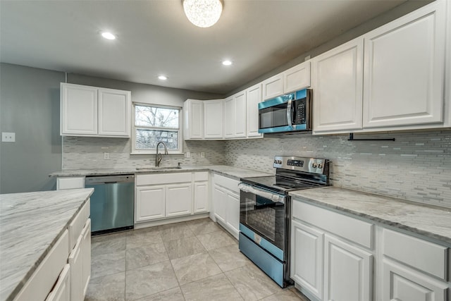 kitchen featuring light stone countertops, appliances with stainless steel finishes, white cabinetry, and a sink