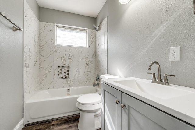 bathroom with toilet, shower / tub combination, wood finished floors, vanity, and a textured wall