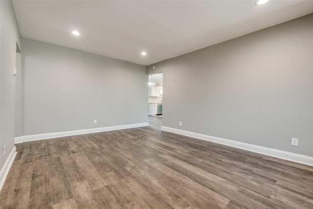 spare room with recessed lighting, baseboards, and dark wood-type flooring