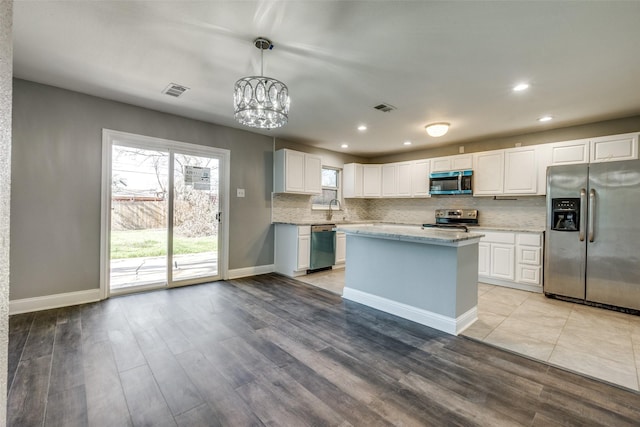 kitchen with visible vents, a chandelier, decorative backsplash, light wood-style flooring, and stainless steel appliances