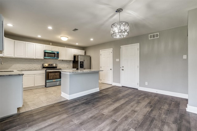 kitchen featuring a kitchen island, visible vents, stainless steel appliances, and a sink