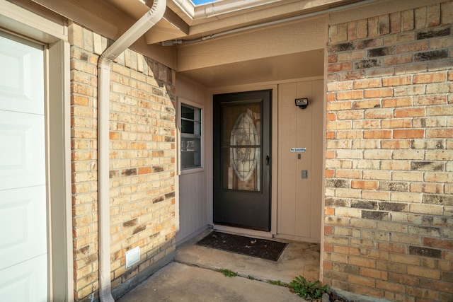 entrance to property with brick siding and an attached garage