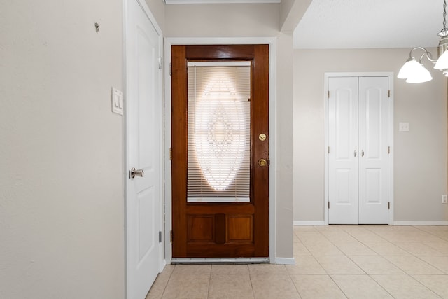 foyer with light tile patterned floors, a chandelier, and baseboards