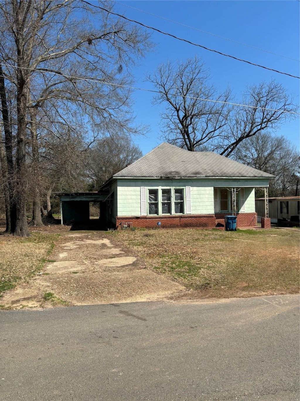 view of front facade with an attached carport, a front yard, and driveway