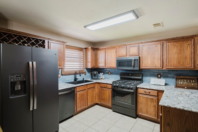 kitchen featuring visible vents, backsplash, appliances with stainless steel finishes, brown cabinetry, and a sink